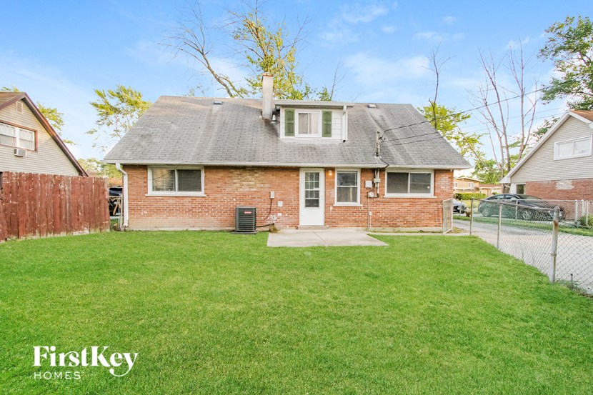 a brick house with a yard and a chain link fence