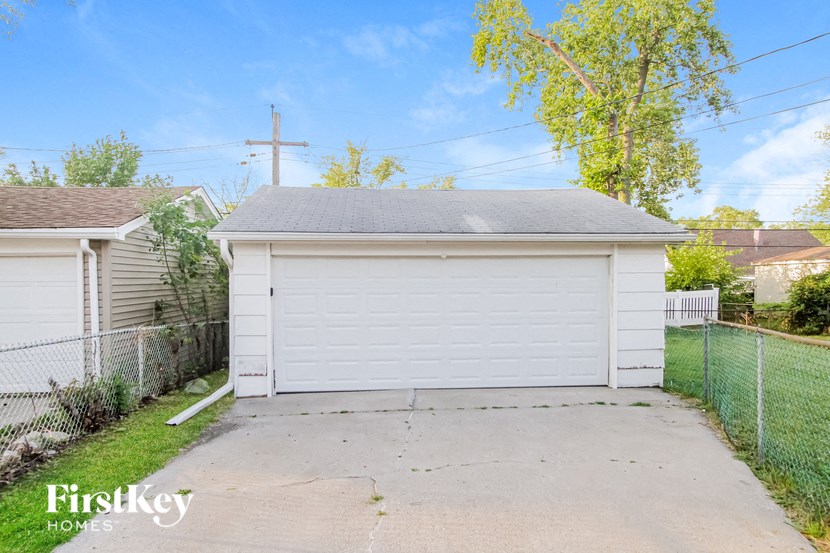 a white garage with a white fence and a driveway