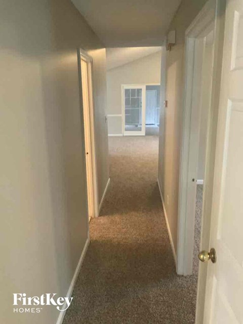 a hallway with a carpeted floor and a door to a bedroom