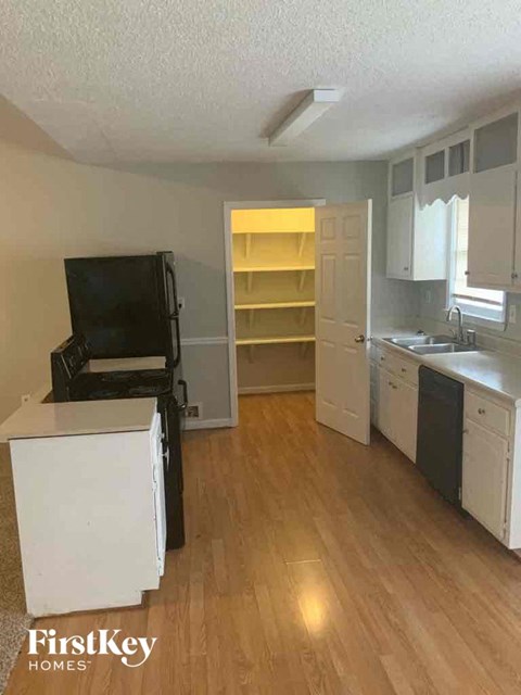 an empty kitchen with a wood floor and white cabinets