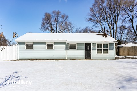A blue house with a snowy front yard.