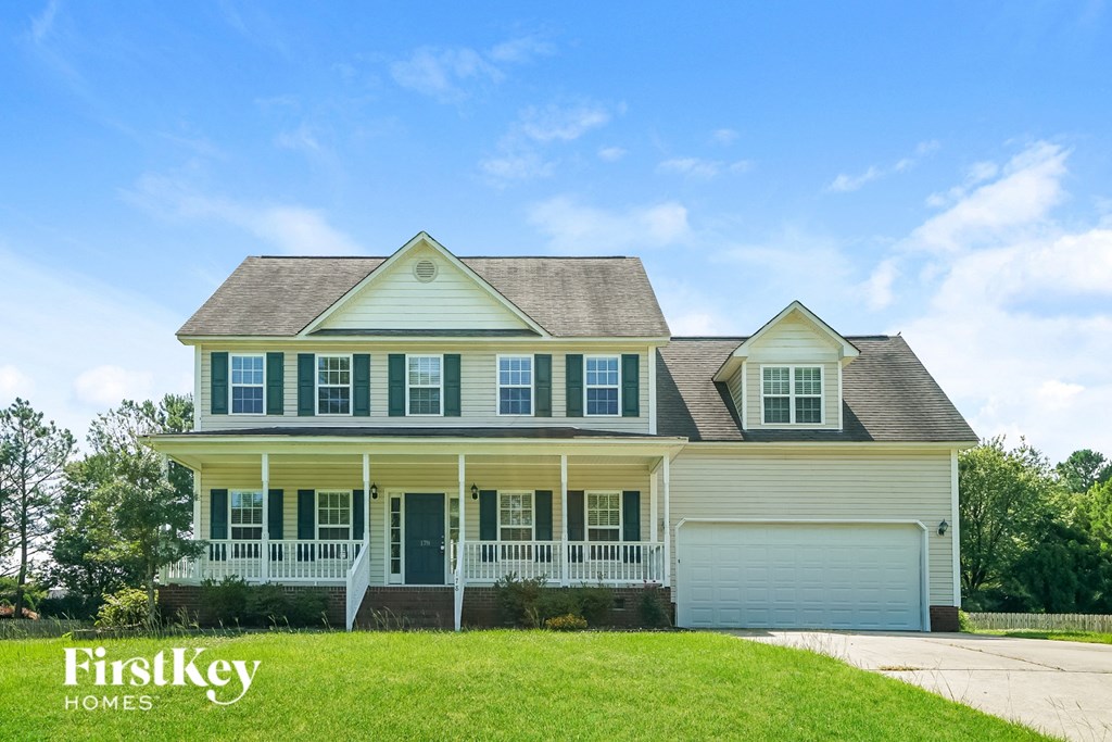 a white house with green shutters and a lawn