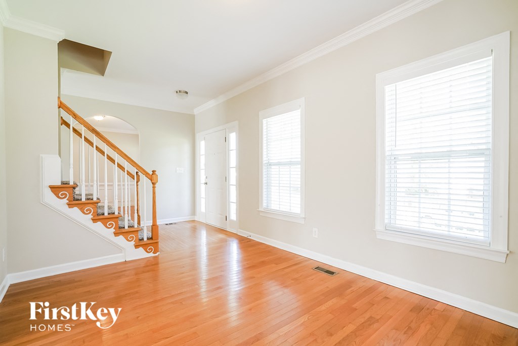 a living room with wood floors and white walls and a staircase