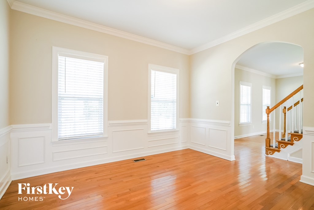 a living room with wood floors and white walls and a staircase