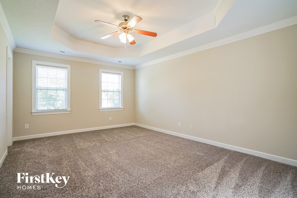 an empty room with a ceiling fan and two windows
