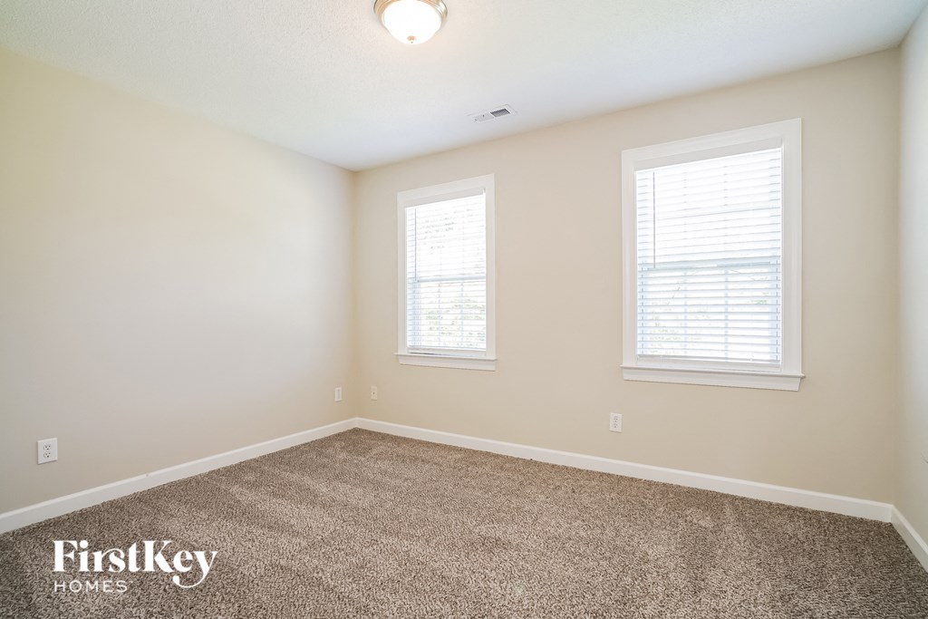 a bedroom with a carpeted floor and two windows