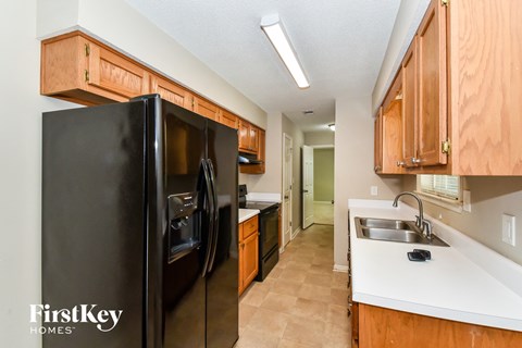 a kitchen with black appliances and wooden cabinets and white counter tops