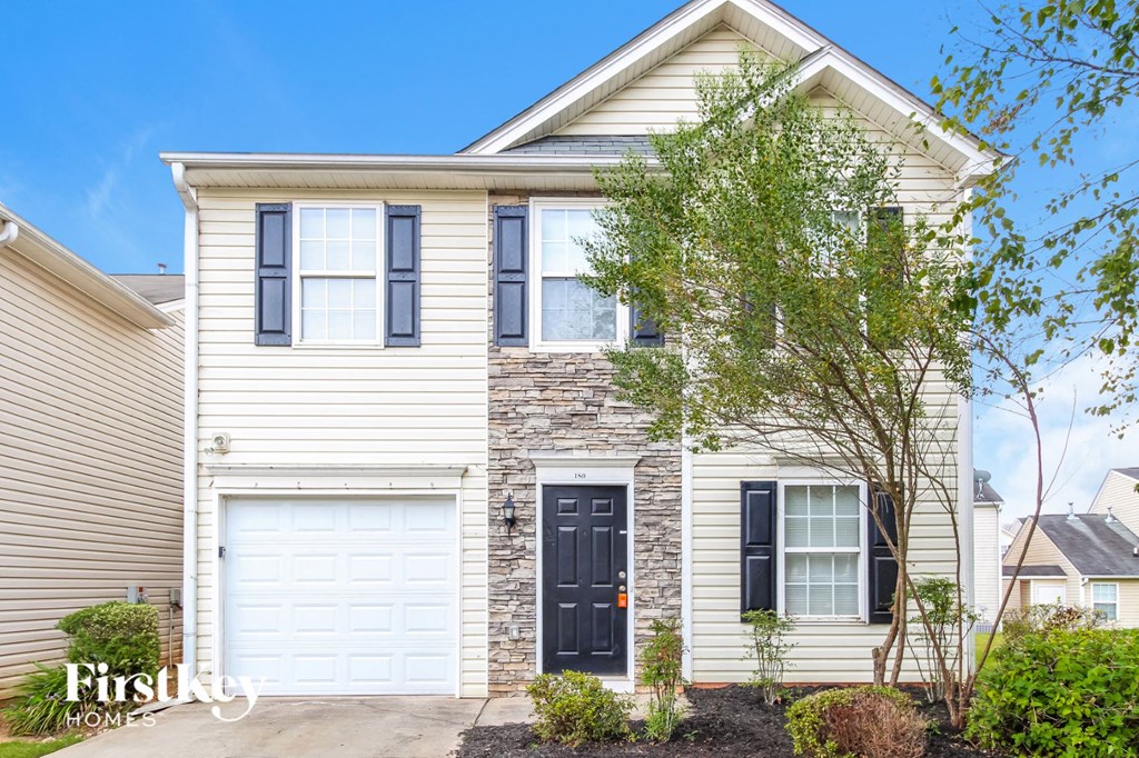 a white house with a black door and two garage doors