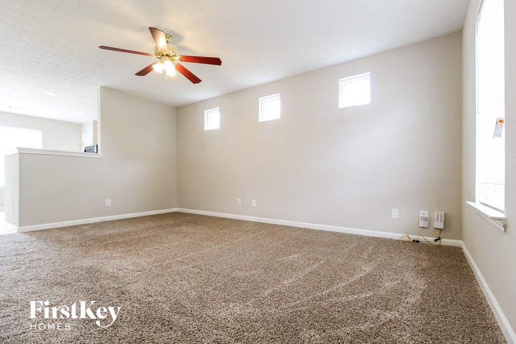 an empty living room with carpet and a ceiling fan