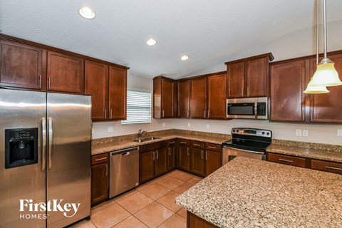 A kitchen with brown cabinets and a granite countertop.