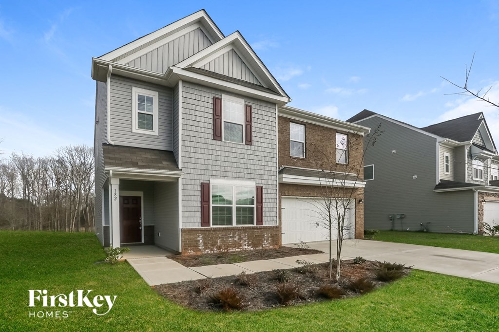 A grey house with a brown tree in front of it.