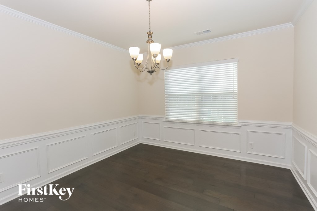 A room with a chandelier and a window with blinds.