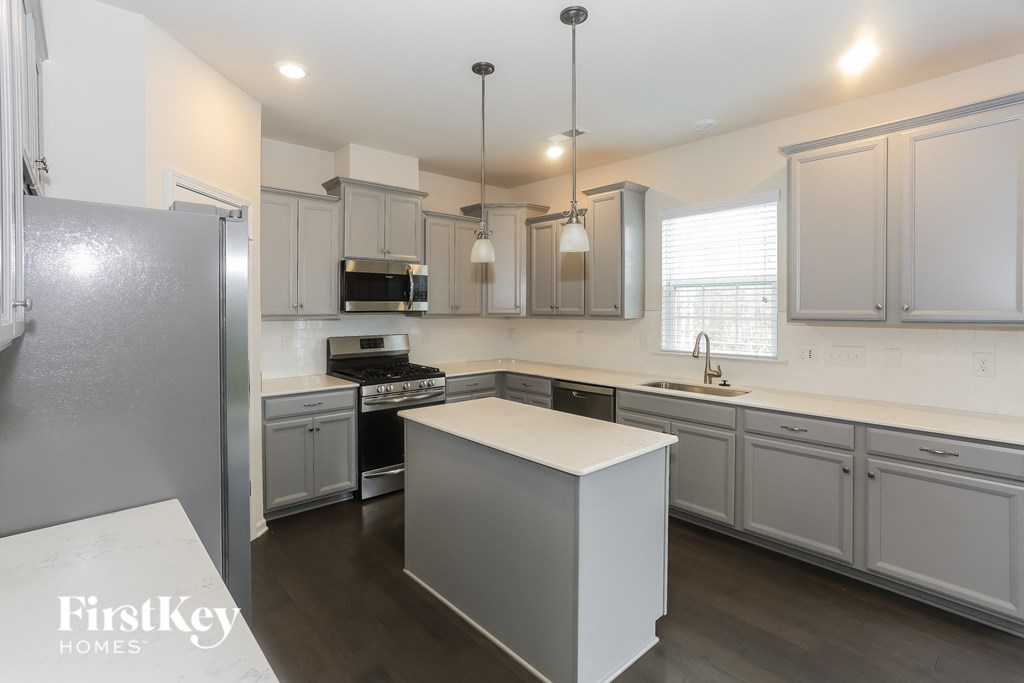 A kitchen with a refrigerator on the left and a countertop with a sink.