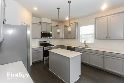 A kitchen with a refrigerator on the left and a countertop with a sink.