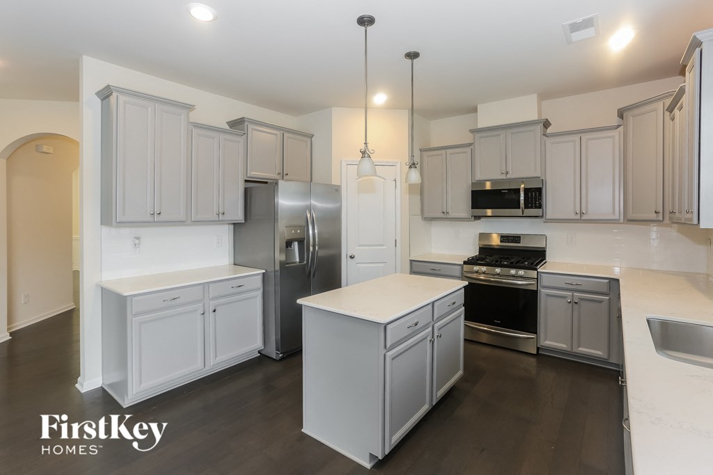 A kitchen with a refrigerator, stove, and cabinets.