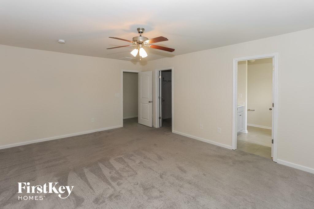 A spacious room with a ceiling fan and two doors.
