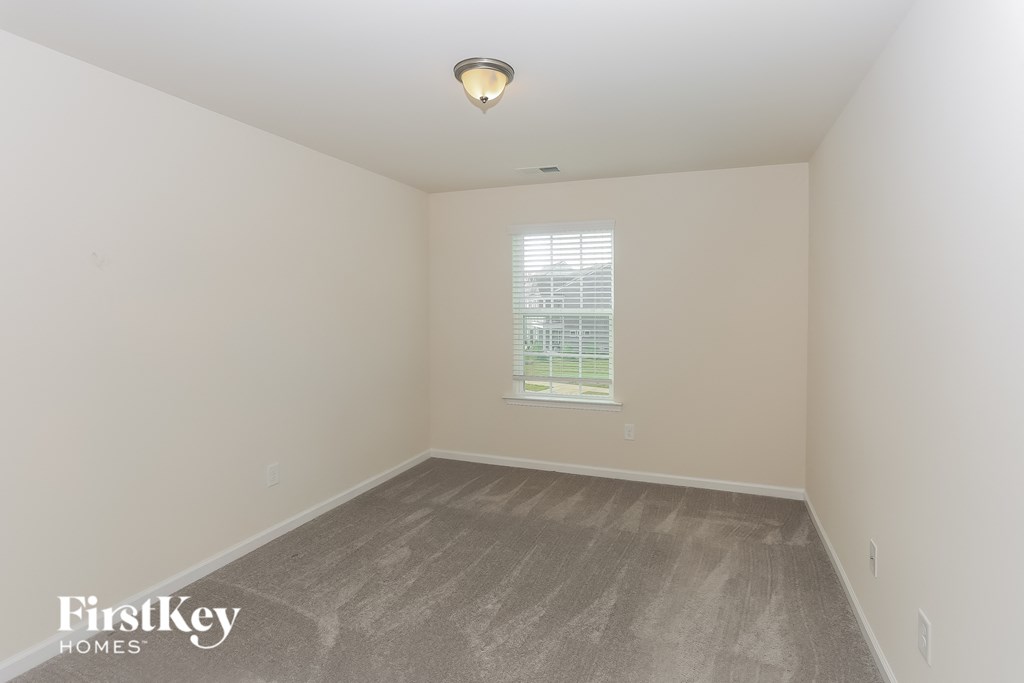 A room with a grey floor and a window with blinds.