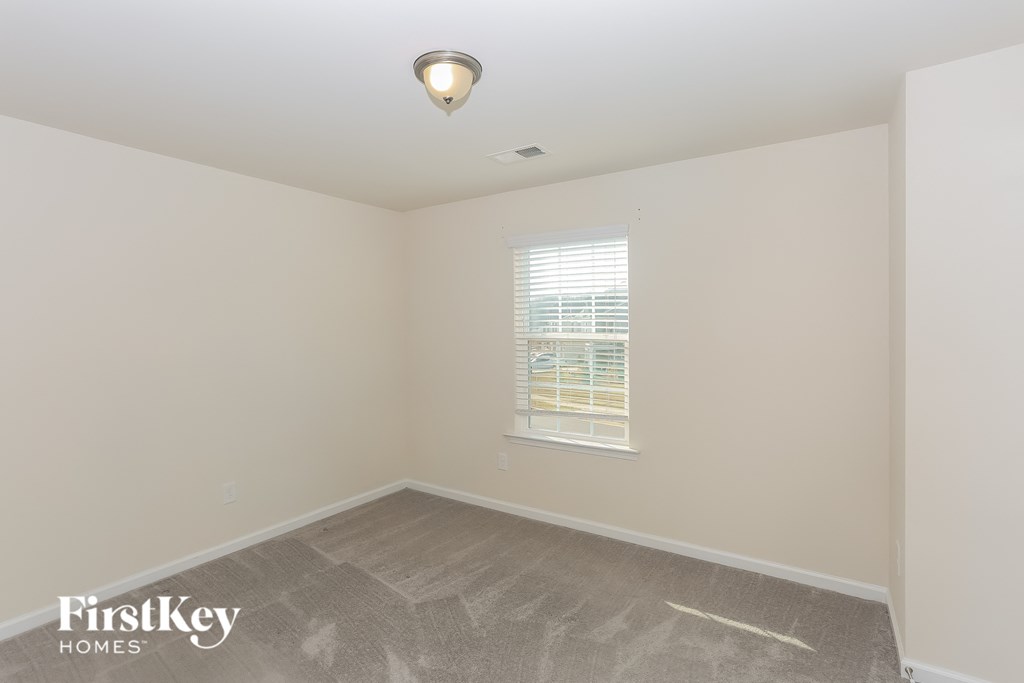 A room with a window and a carpeted floor.