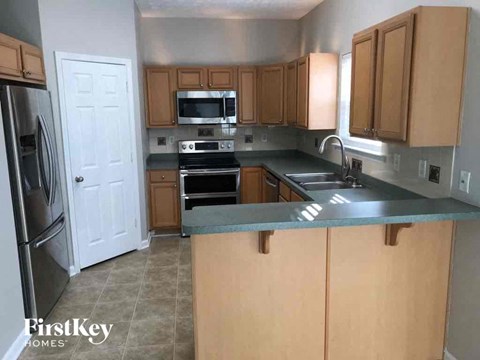 A kitchen with wooden cabinets and a stainless steel refrigerator.