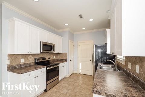 A kitchen with a granite counter top and white cabinets.