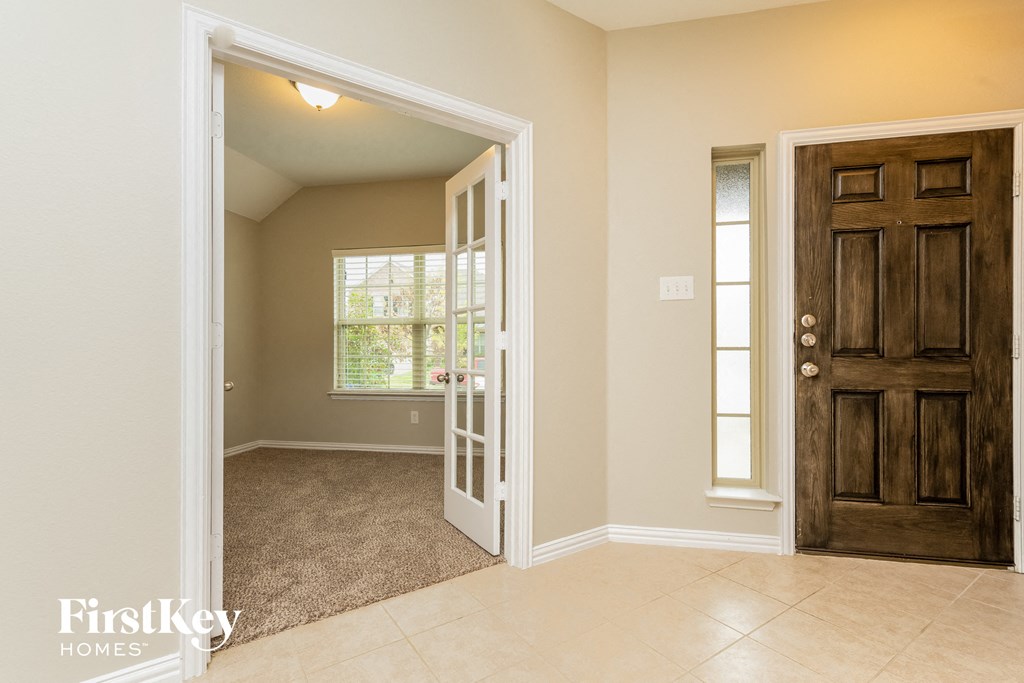 A room with a brown door and a window with blinds.