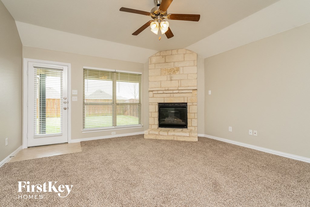 A living room with a fireplace and a ceiling fan.