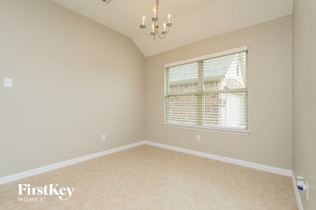 A room with a chandelier, a window with blinds, and a FirstKey Homes logo on the wall.