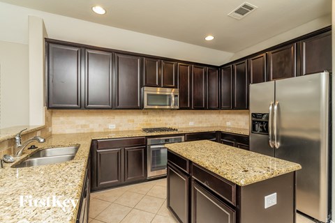 A kitchen with brown cabinets and granite countertops.