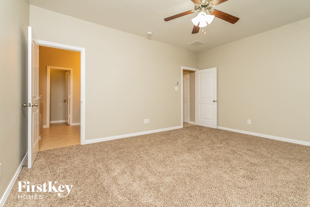 A spacious room with a carpeted floor and a ceiling fan.