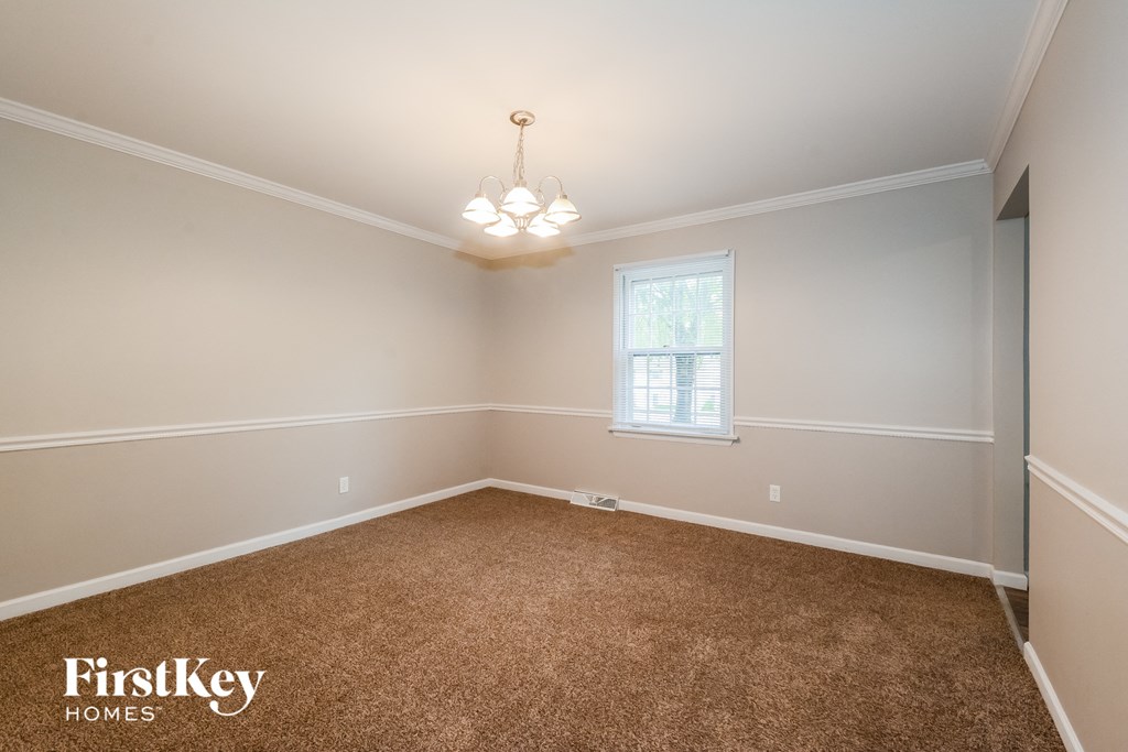 A room with a carpeted floor and a chandelier hanging from the ceiling.