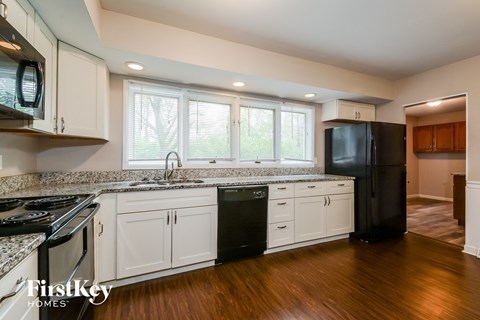A kitchen with white cabinets and a black fridge.