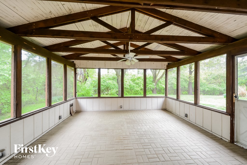 A sunroom with a tiled floor and a ceiling fan.