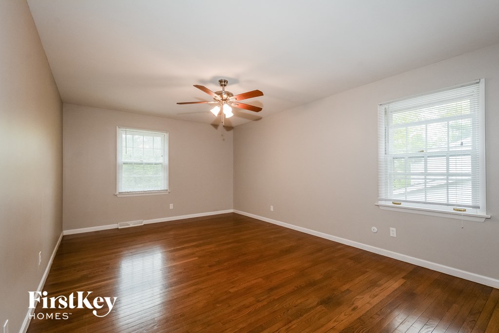 A room with a ceiling fan and wooden flooring.