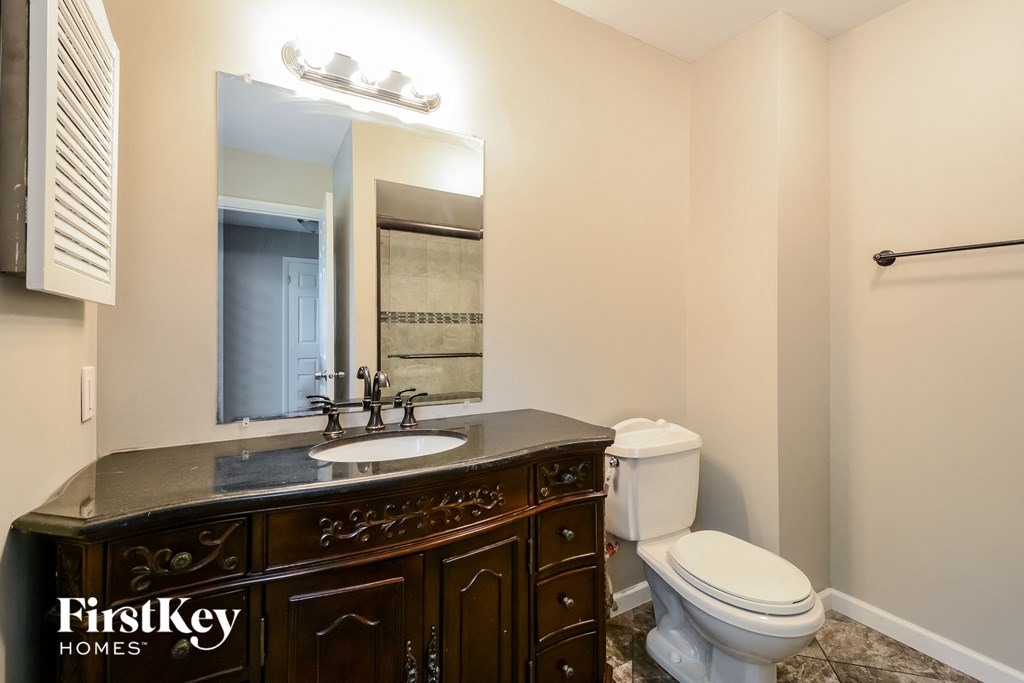 A bathroom with a sink, toilet and mirror.