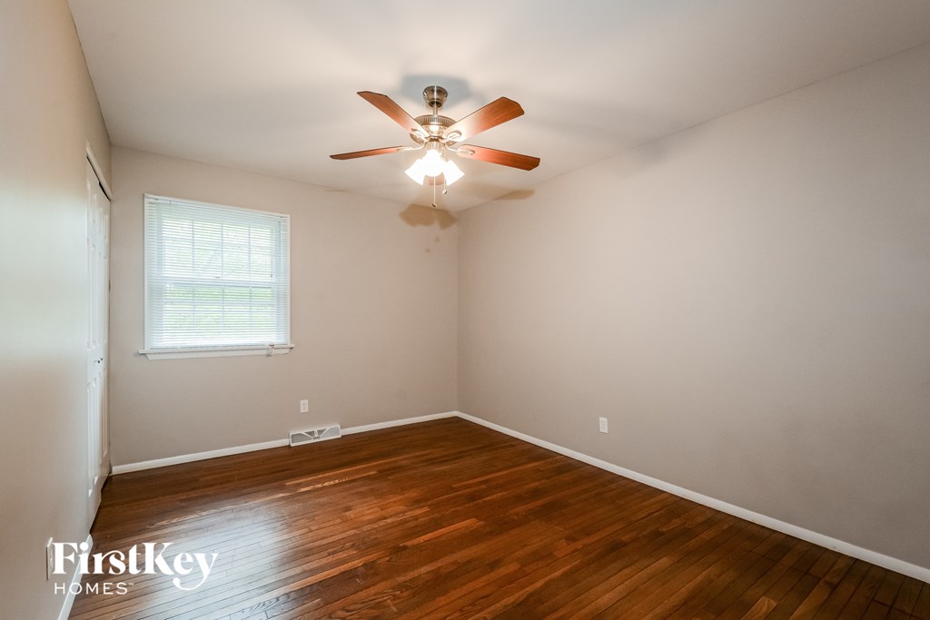 A room with a ceiling fan and wooden flooring.