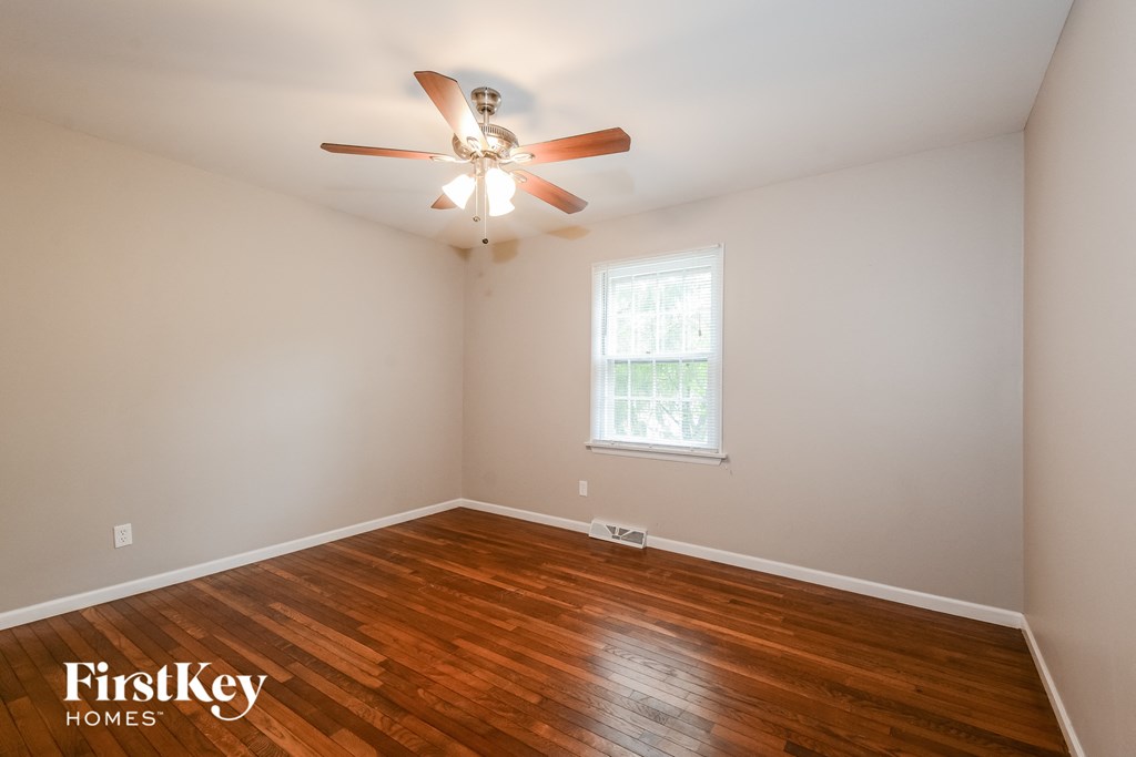A room with a ceiling fan and wooden flooring.