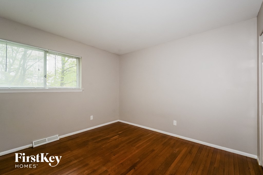 A room with wooden floors and a window with blinds.