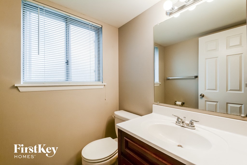 A bathroom with a toilet, sink, and mirror.