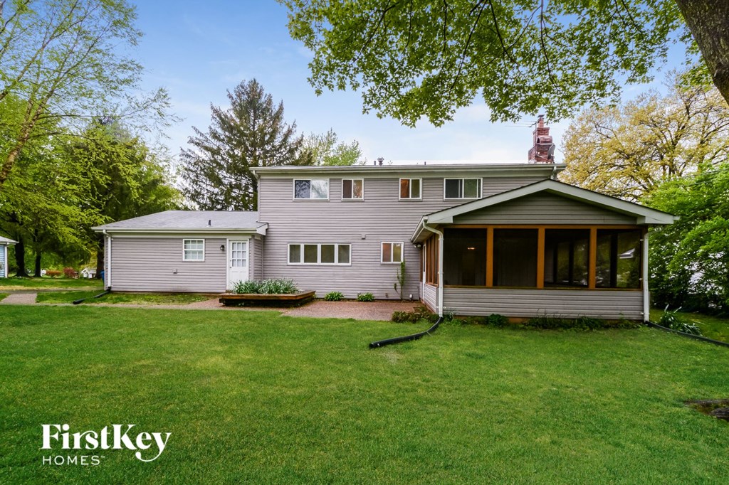 A house with a grey roof and a brown door is surrounded by green grass.
