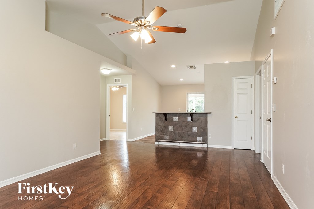 A spacious room with a ceiling fan and wooden flooring.