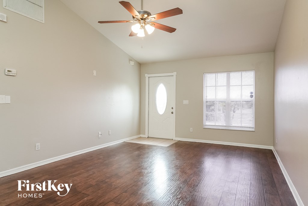 A room with a fan and wooden floors.