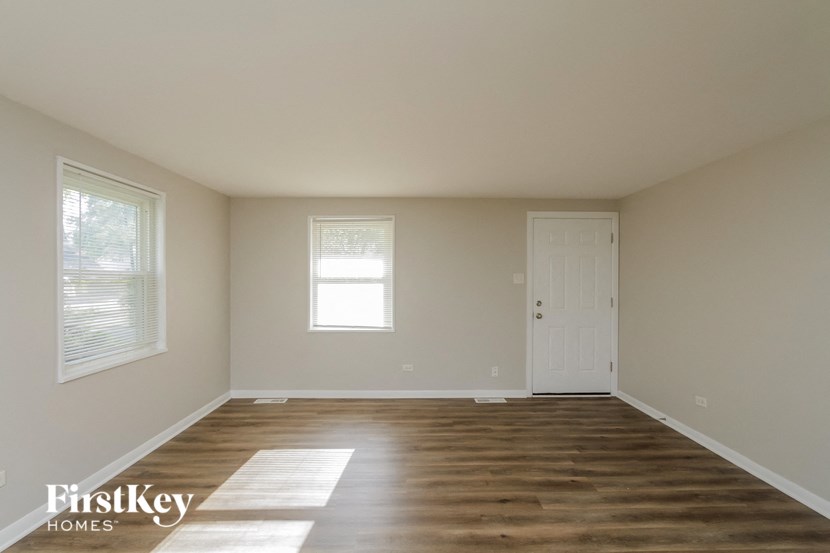 an empty living room with wooden floors and a white door