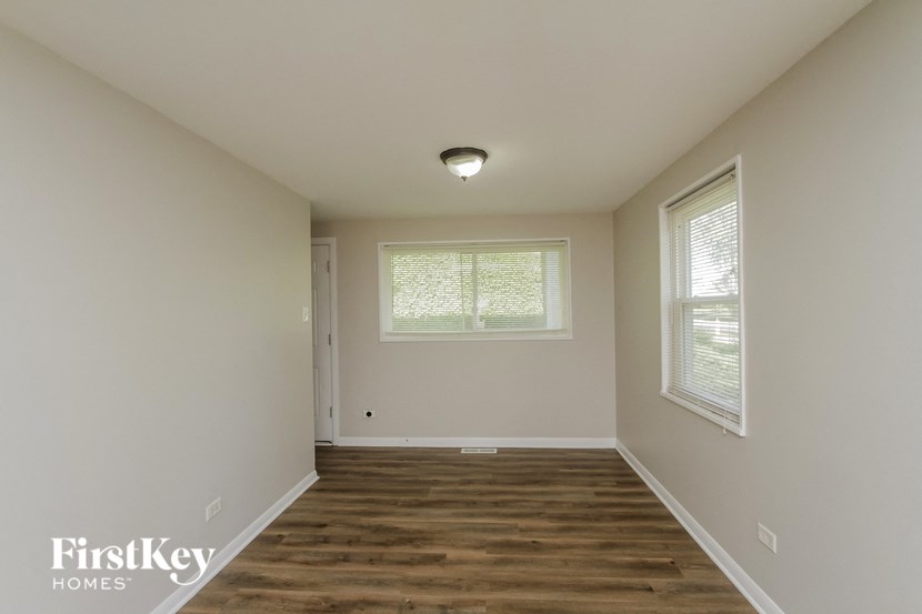 the spacious living room with wood flooring and white walls