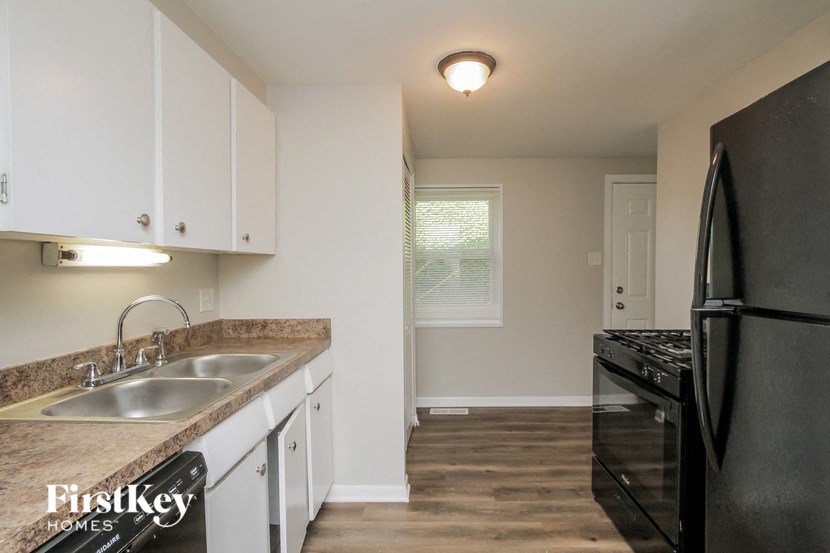 an empty kitchen with black appliances and white cabinets