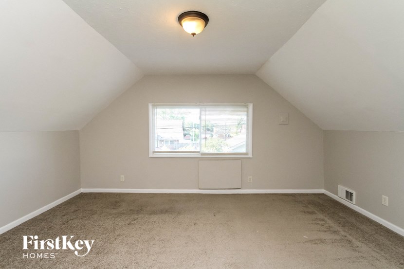 the bedroom has a carpeted floor and a large window