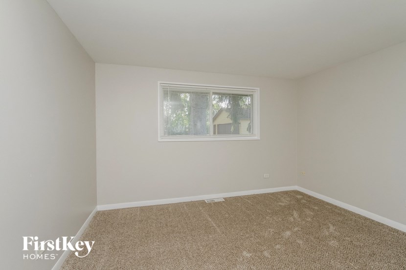 a bedroom with white walls and carpet and a window