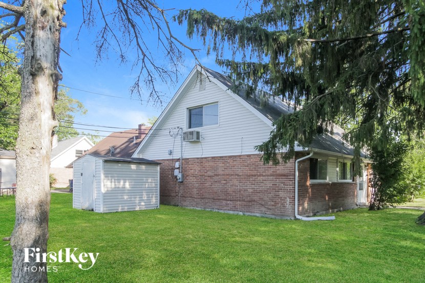 a brick house with a garage and a tree in the yard