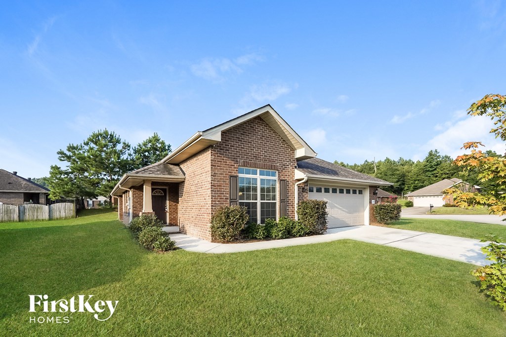 a small brick house with a lawn and a driveway