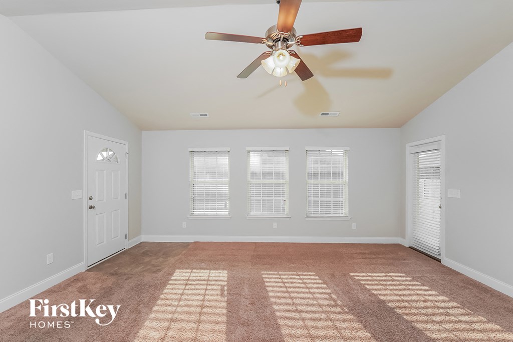a living room with a ceiling fan and a carpet