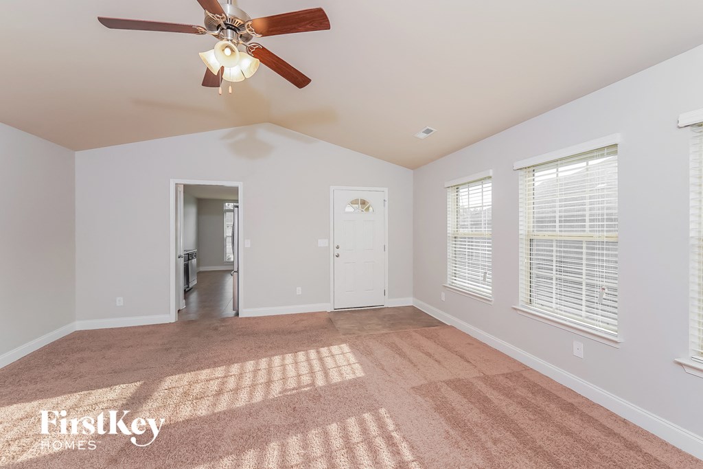 a living room with a ceiling fan and a carpet